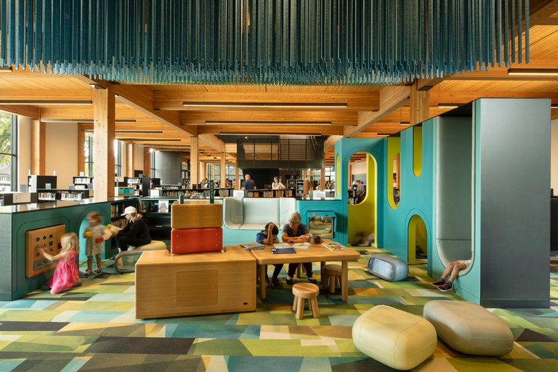 Children's area with vertical glass rod installation overhead, timber play structures and patterned floor tiles in daylight