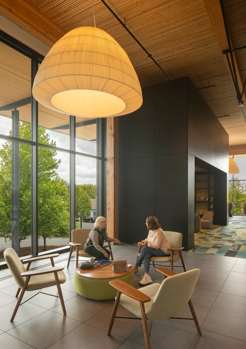 Seating alcove with oversized pendant fixture, lounge chairs, and window overlooking trees outdoors