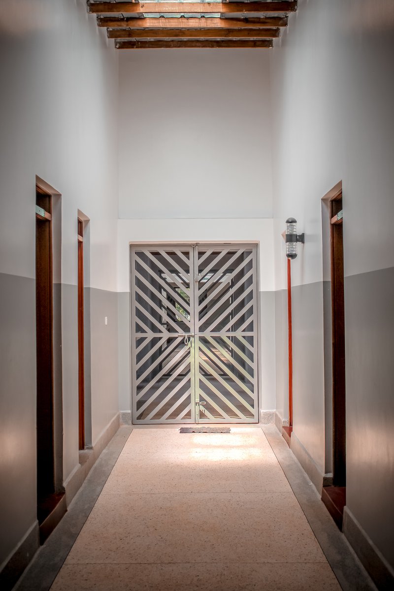 Corridor view toward double doors with diagonal timber slat pattern and exposed roof beams overhead