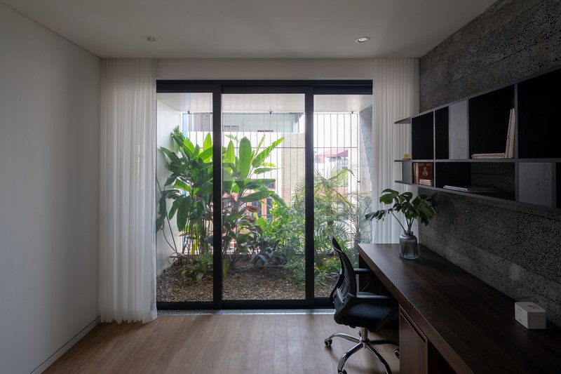 Home office with glazed doors opening to an interior garden courtyard with palms and grasses