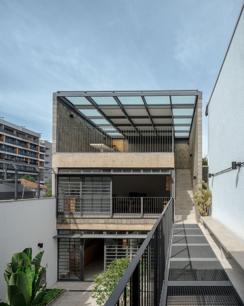 Courtyard view showing stacked terraces with glass canopy, perforated metal balustrades, and metal mesh walkway