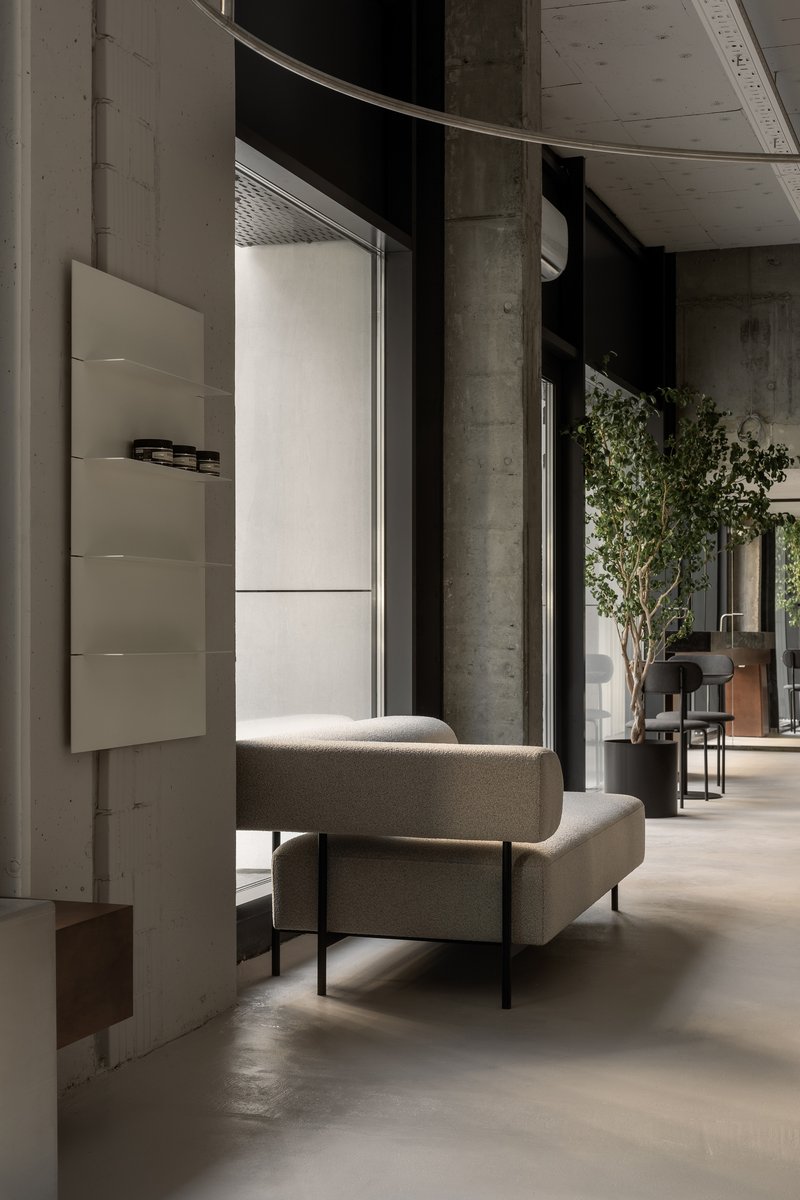 Seating alcove with concrete columns, floating display cabinet, curved metal track, and view toward planted areas