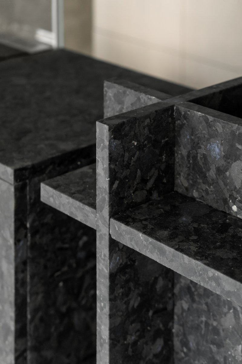 Detail of black terrazzo stone shelving with mitred corner joints and visible aggregate
