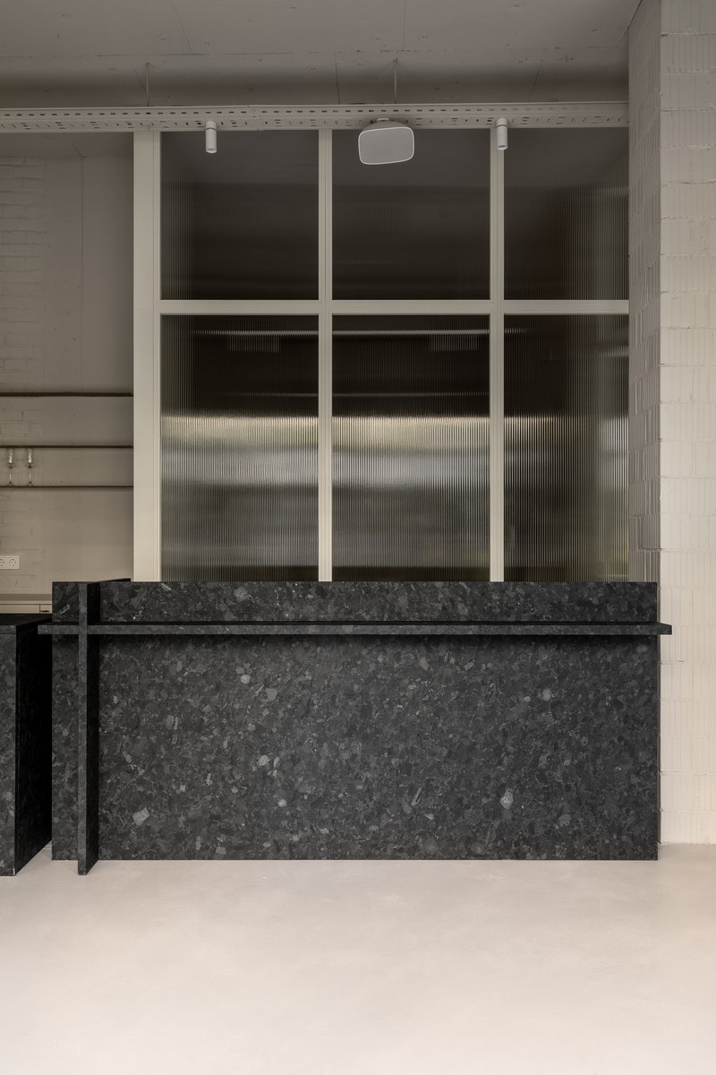 Dark stone counter with gridded translucent glass partition and white painted brick walls