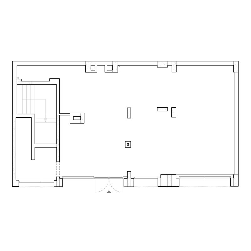 Floor plan drawing showing a large open space with a staircase and service areas along the left side
