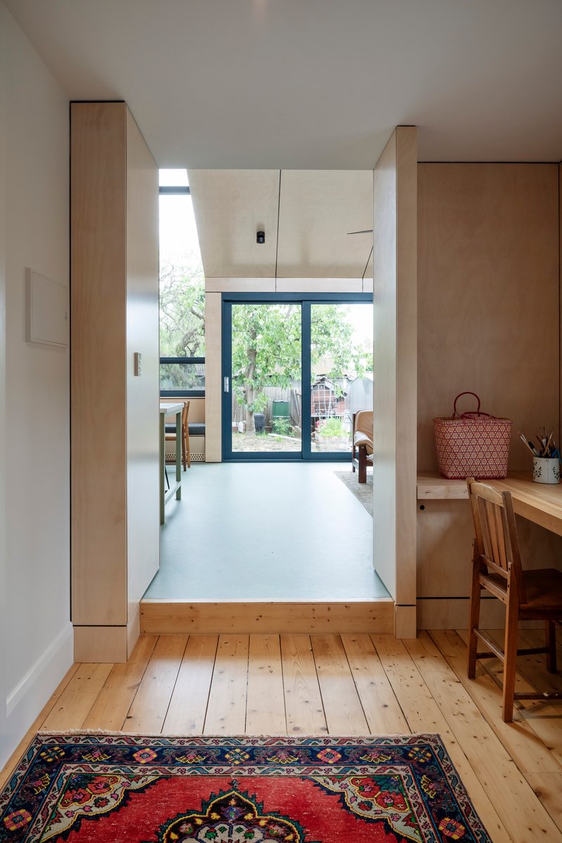 Interior view through timber-framed doorway to kitchen and glazed doors opening onto garden