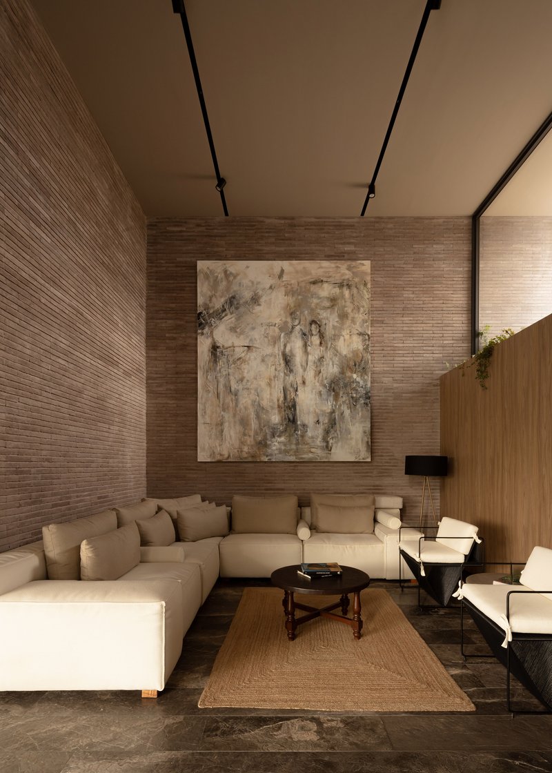Double-height living room with horizontal brick walls and recessed ceiling track lighting