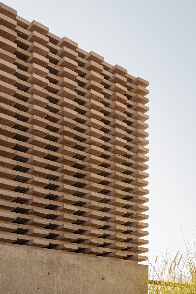 Detail of horizontal timber slat screen cantilevering over concrete base under overcast sky