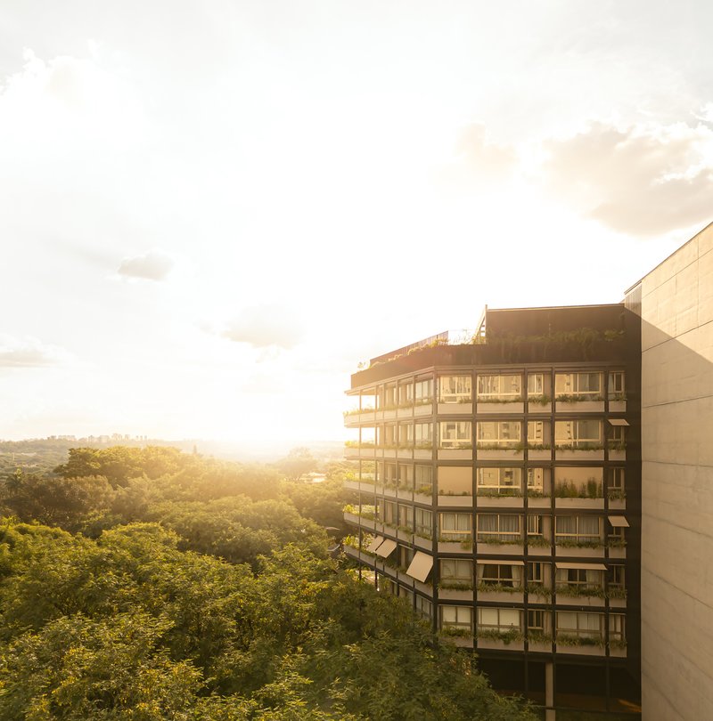 Glass and concrete facade with continuous balconies overlooking a forested landscape at sunset