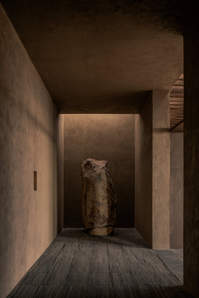 Recessed alcove with backlit wall displaying a weathered ceramic vessel on timber decking