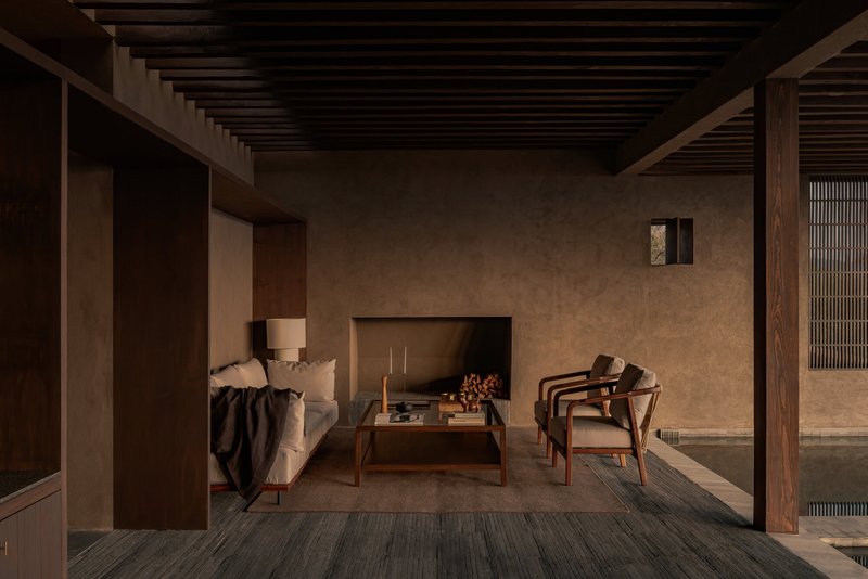 Sitting area with inset fireplace and timber-framed openings connecting to adjacent interior spaces