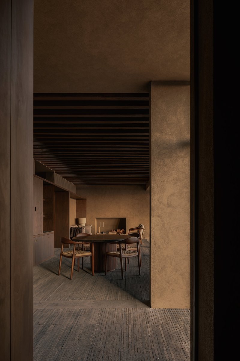 Doorway view into dining space with slatted ceiling and textured concrete walls