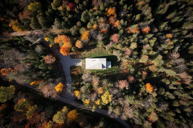 Aerial view of the white gabled roof surrounded by deciduous forest in autumn