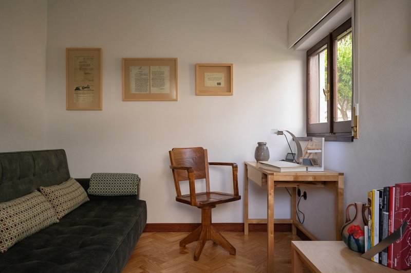 Interior workspace with herringbone wood flooring and three framed documents on white walls