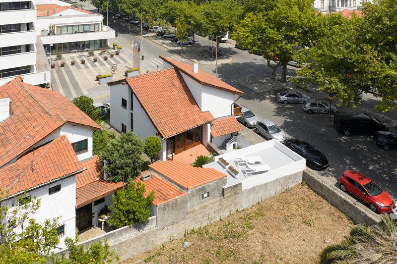 Overhead view of clustered terracotta roofs with concrete courtyard wall and parked cars