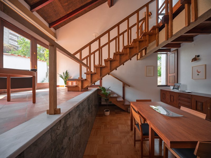 Split-level interior showing timber staircase with grid railings and herringbone wood flooring below