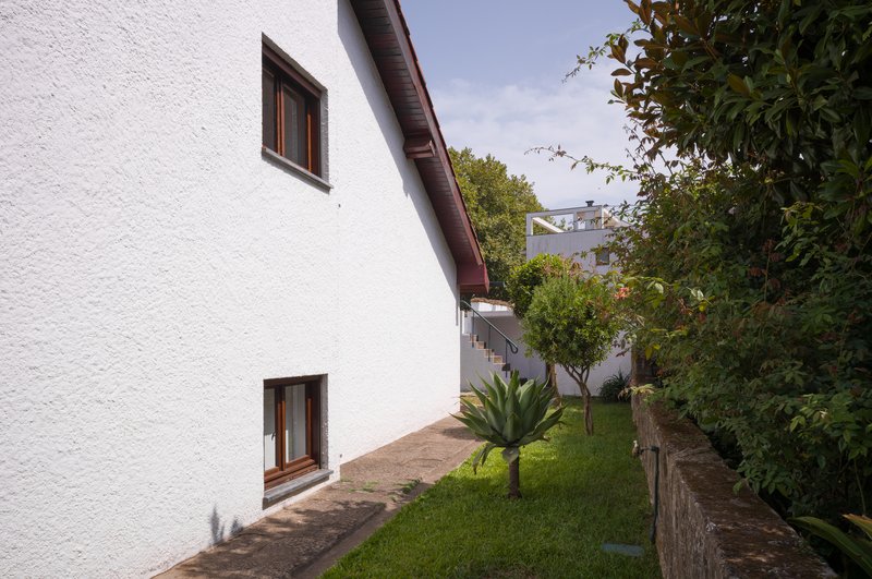 White stucco facade with timber-framed windows alongside a sloped garden path with an agave plant