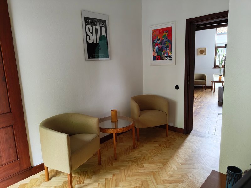 Corridor with herringbone parquet flooring and two upholstered chairs framing a view through a doorway