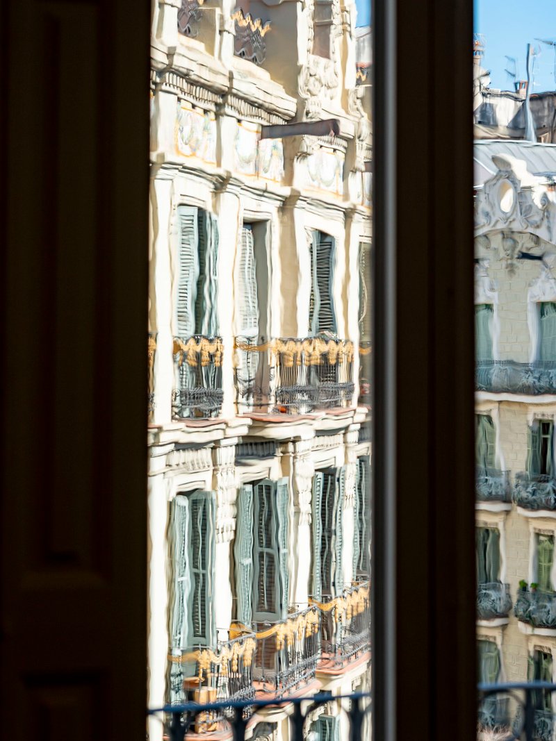 View through the window to the neighboring facades with ornamental balconies in afternoon sunlight