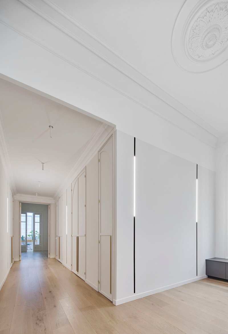 Long hallway with white paneled wardrobes, ceiling rose medallion and vertical black pendant light fixtures
