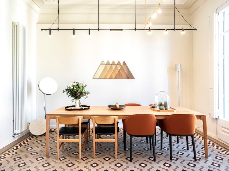 Dining area with timber table, mixed seating, and patterned tile floor under suspended track lighting