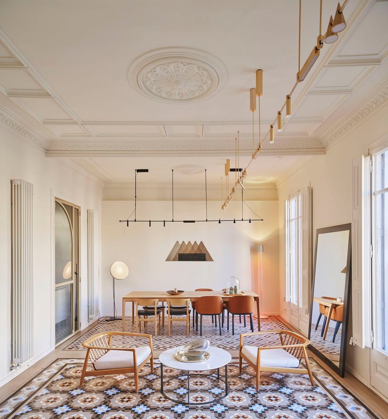 Living and dining area with patterned tile floor, coffered ceiling, and brass chandeliers overhead