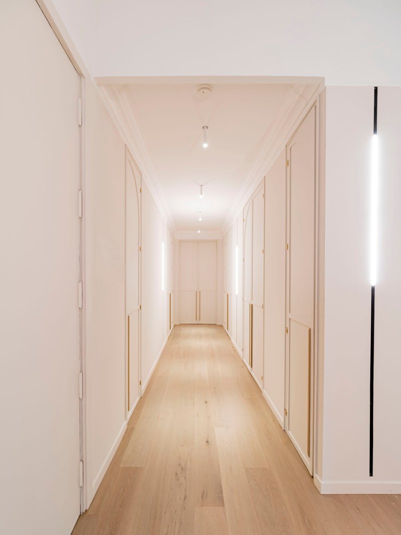 Light wood flooring corridor with flush white paneled doors and recessed ceiling lights