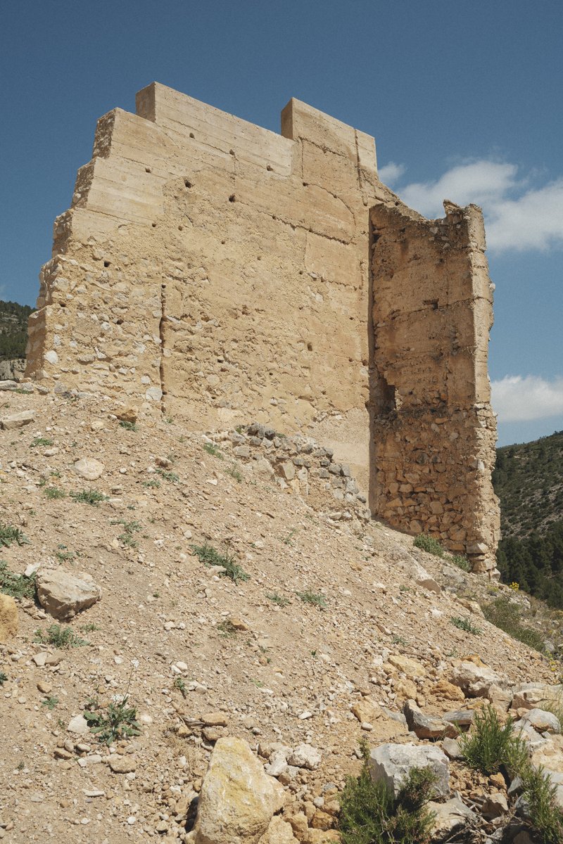 Close view of reconstructed tower wall with visible beam pockets on a steep gravel slope