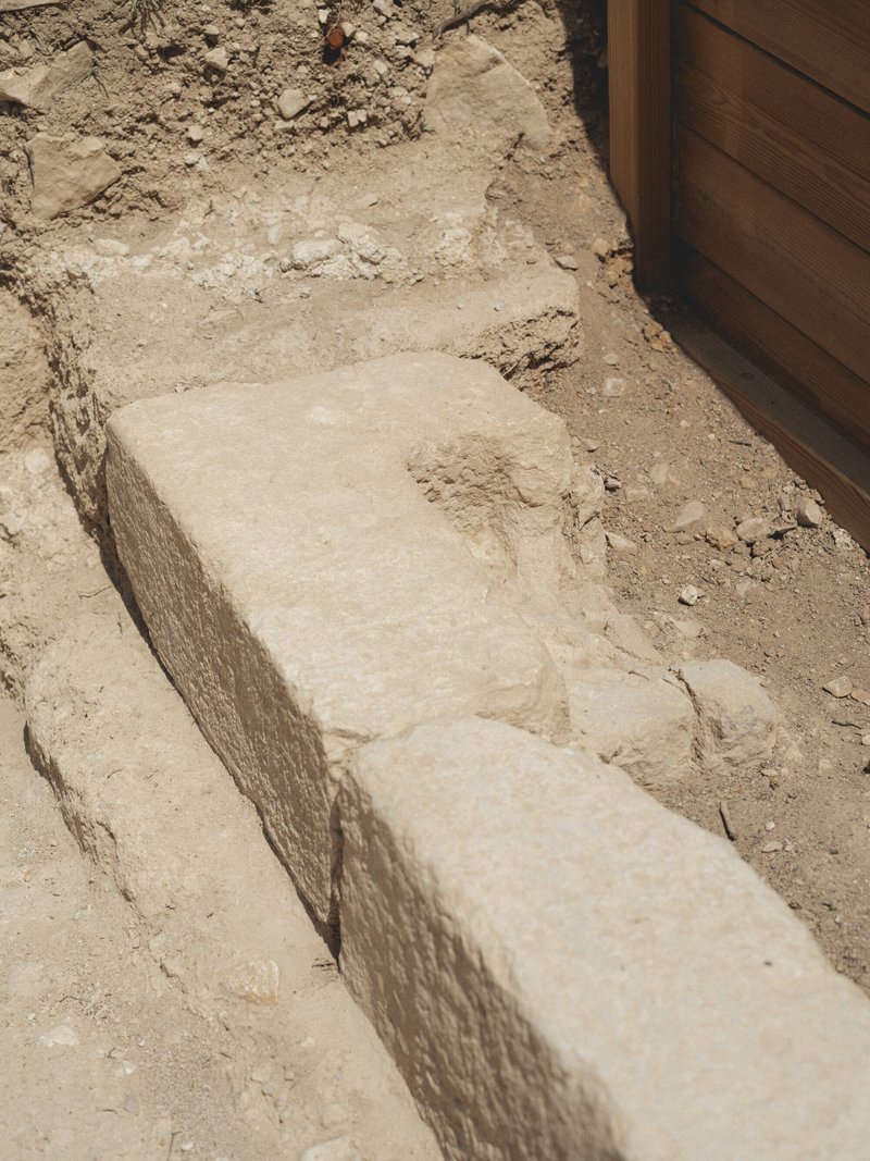 Cut stone blocks forming steps in excavated earth beside timber wall edge
