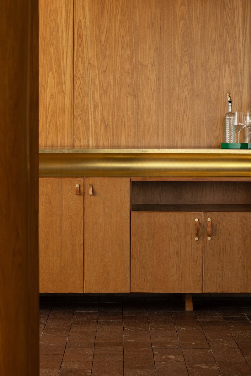 Close-up of walnut cabinetry with brass hardware and integrated LED strip lighting at countertop