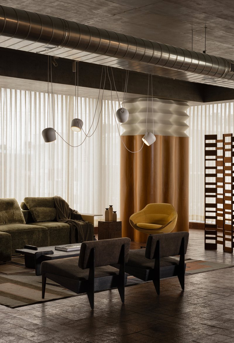 Interior lounge with exposed spiral ductwork overhead and pendant lights suspended by draped cables