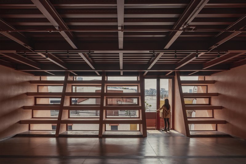 Interior library space with exposed timber ceiling beams and a figure at the window