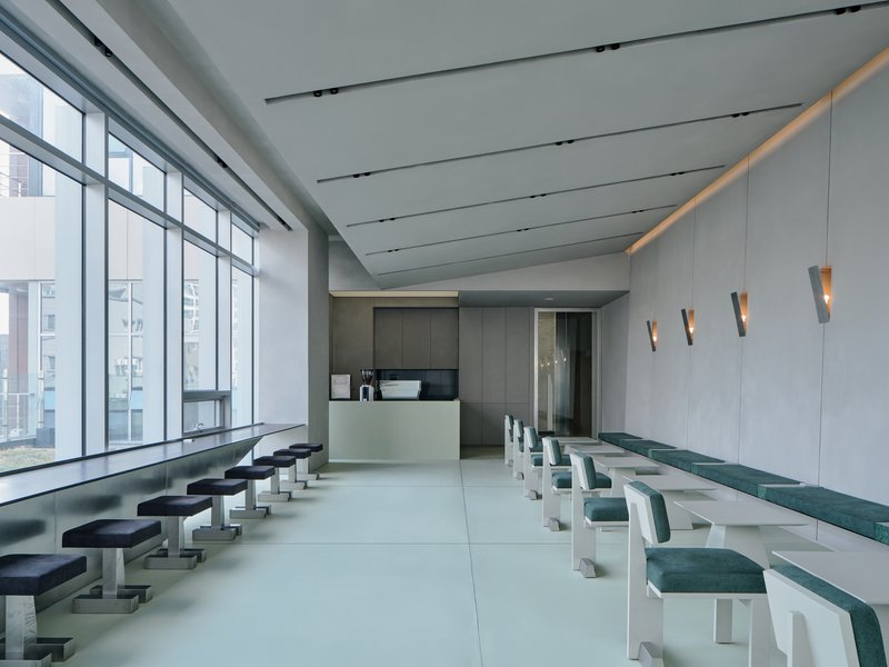 Reception desk with backlit frosted counter and dark grey joinery beneath linear ceiling slots