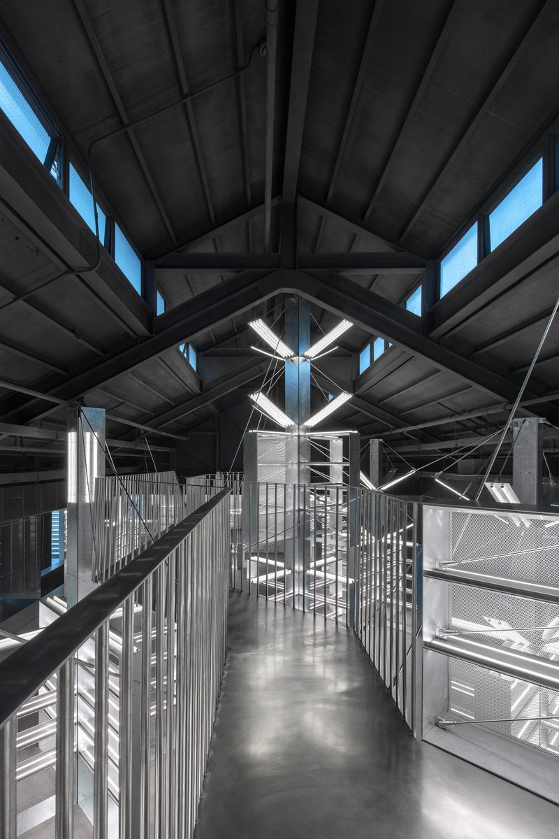 Upper level walkway with metal railings beneath exposed timber trusses and clerestory windows