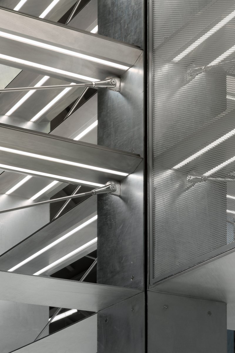 Detail of perforated metal panel meeting steel shelf supports at a concrete column