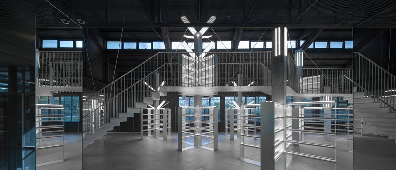 Double-height interior with symmetrical staircases, exposed steel trusses and blue-hour light through glazing