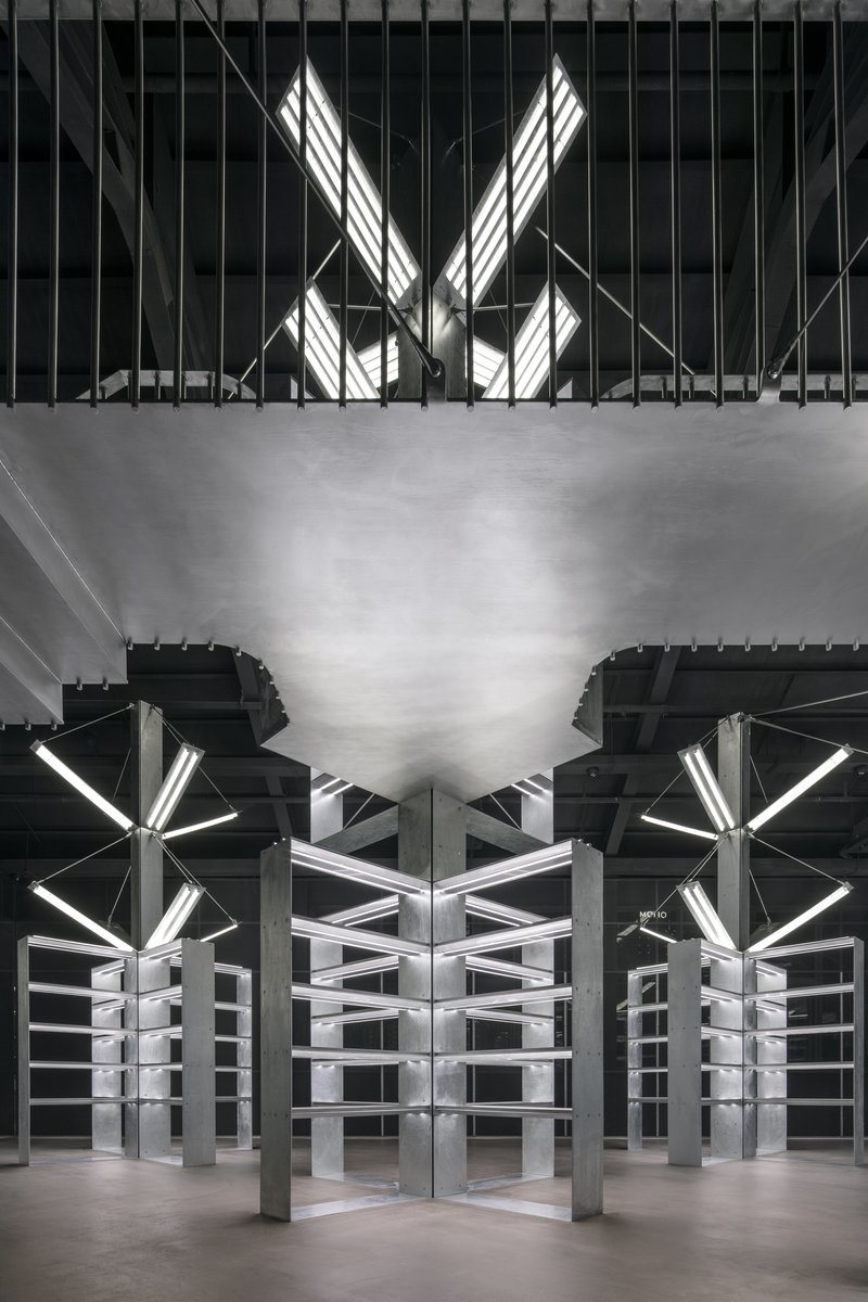 Symmetrical view of white metal shelving units beneath exposed structure and angular skylights