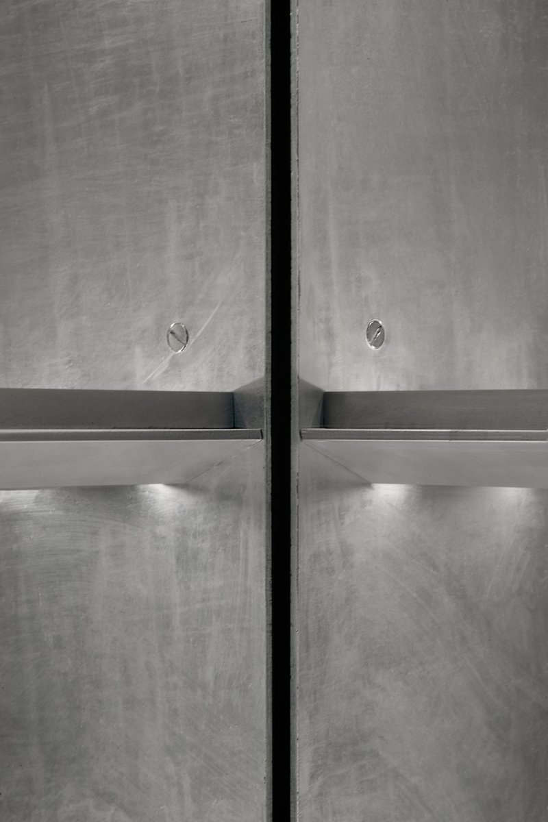 Close-up of concrete wall joint with horizontal metal ledge and integrated lighting below