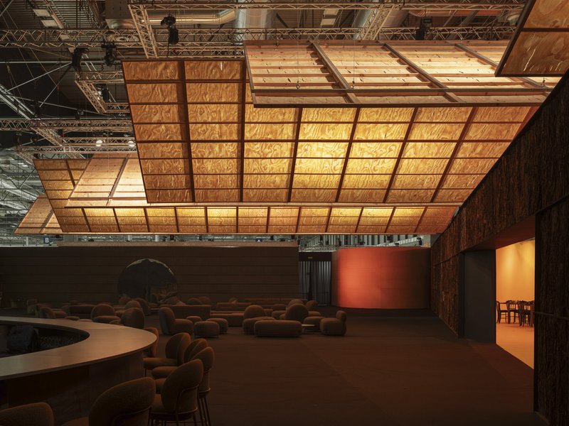 Long view of the luminous gridded ceiling canopy floating over the exhibition hall with curved seating zones