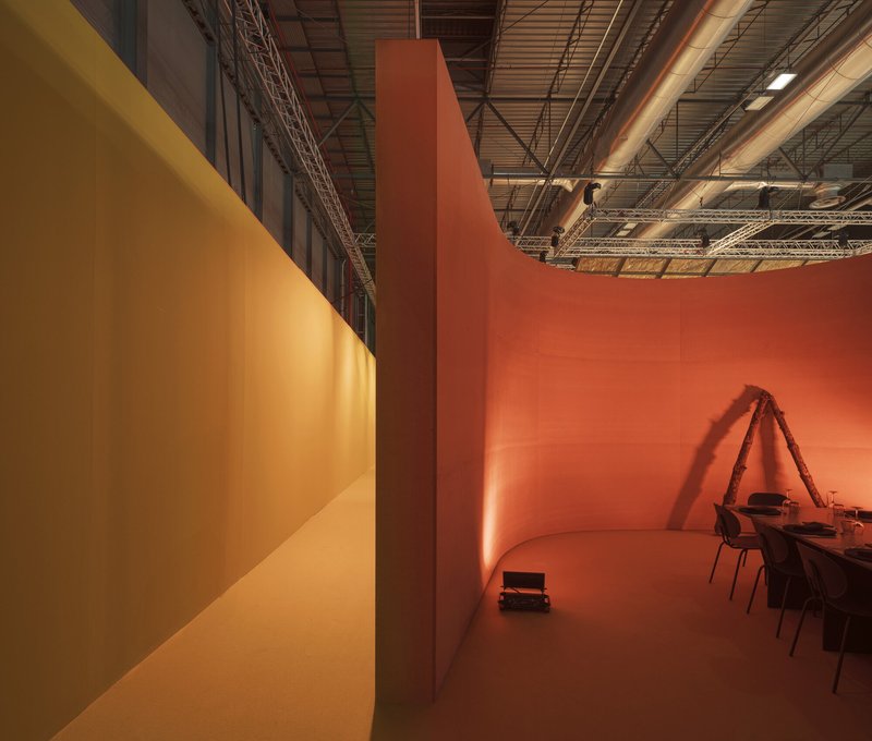 Corner meeting of ochre and terracotta painted walls beneath exposed industrial ceiling trusses