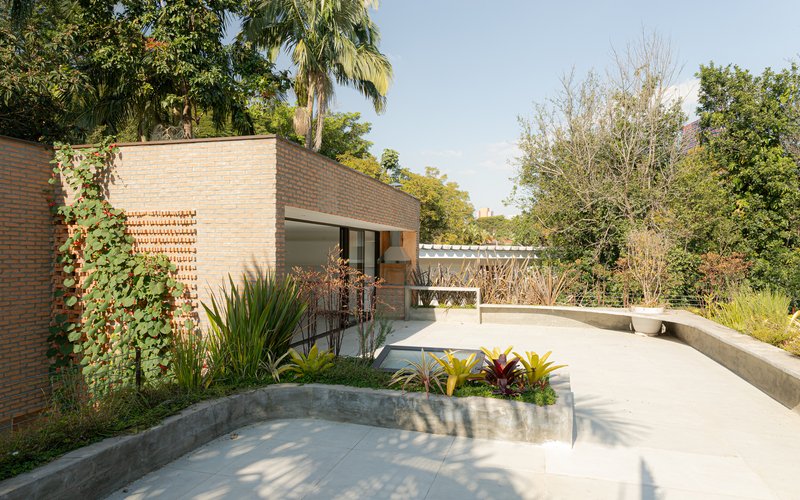 Exterior terrace with curved concrete planters and brick walls beneath a pergola structure