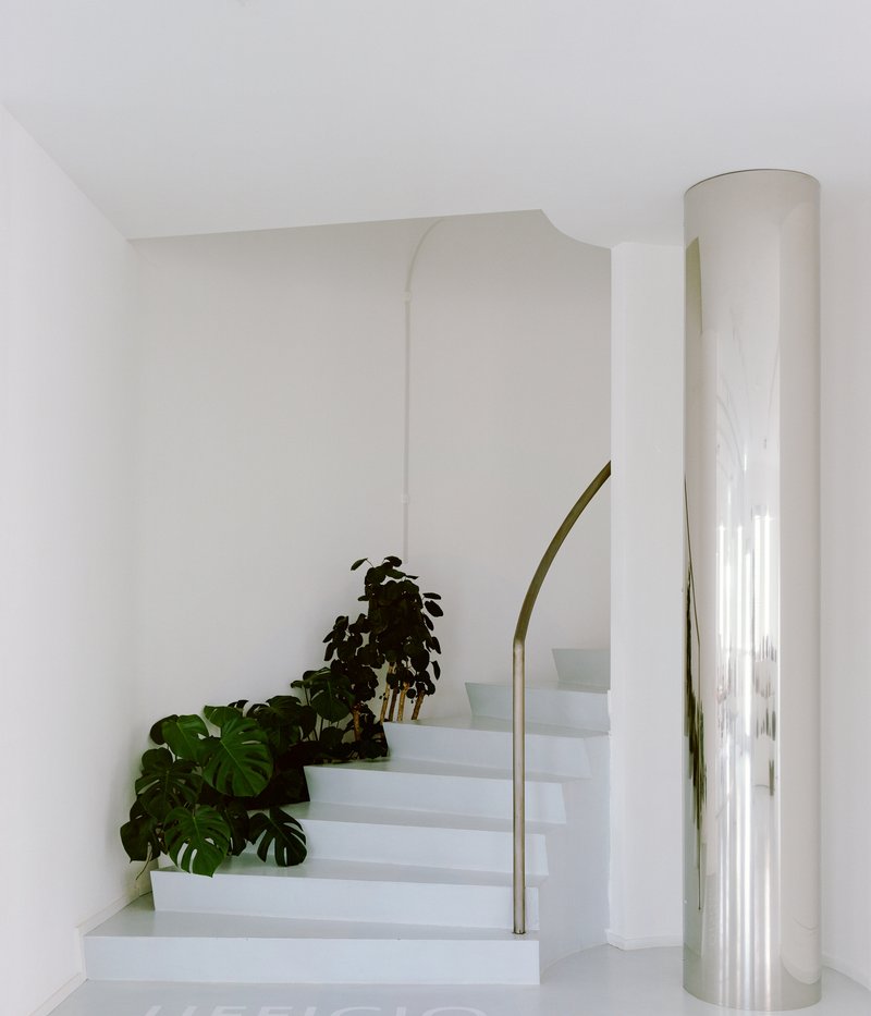 White interior staircase with curved handrail and potted plants beside the steps