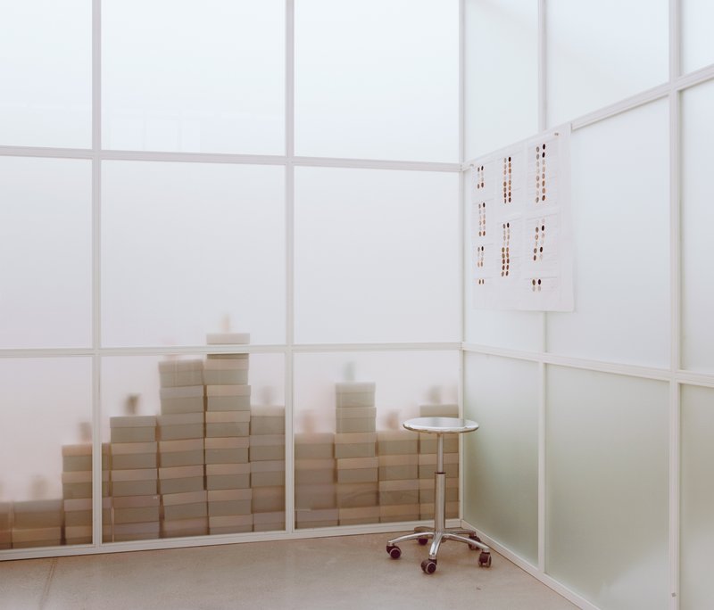 Interior corner with translucent partition panels and stacked boxes visible through the glass