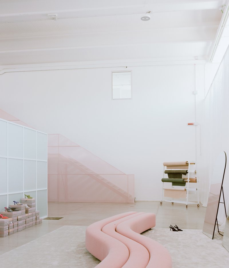 Light-filled room with pale pink staircase and curved pink seating beneath white timber ceiling
