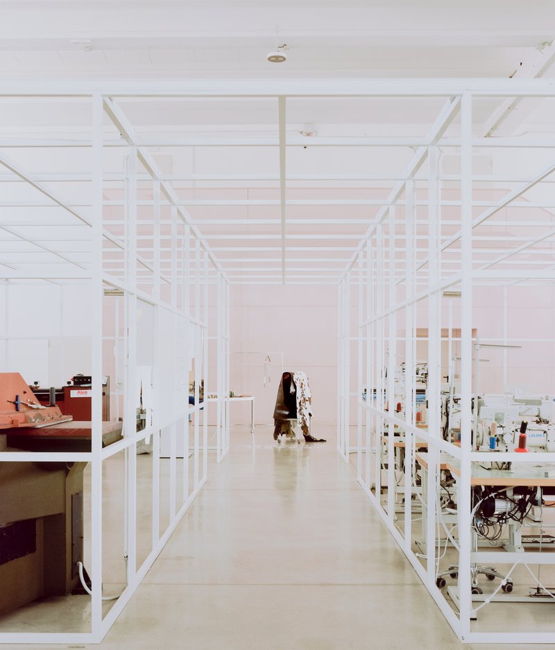Aisle between white metal storage racks with person walking through the showroom