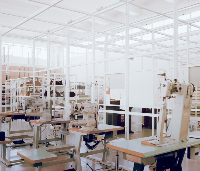 Open studio space with white metal grid ceiling and sewing machines on plywood tables
