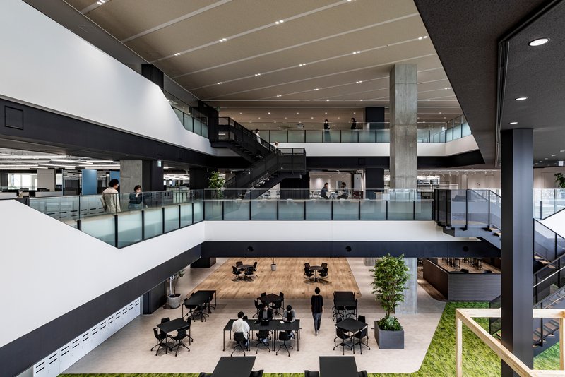 View down into a multi-story atrium with glass guardrails and a person walking below