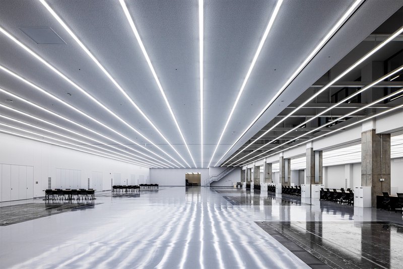 Expansive interior hall with parallel LED light strips radiating across the polished floor and ceiling