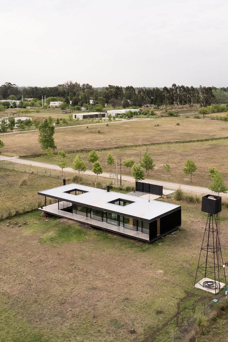 Aerial view of the elevated white-roofed pavilion with two courtyards in an open grassland with water tower