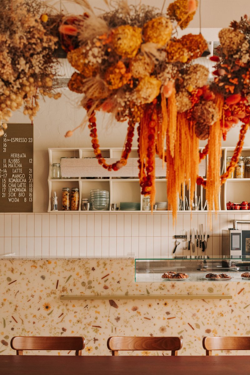 Counter with terrazzo embedded with flowers beneath suspended dried floral arrangements and garlands